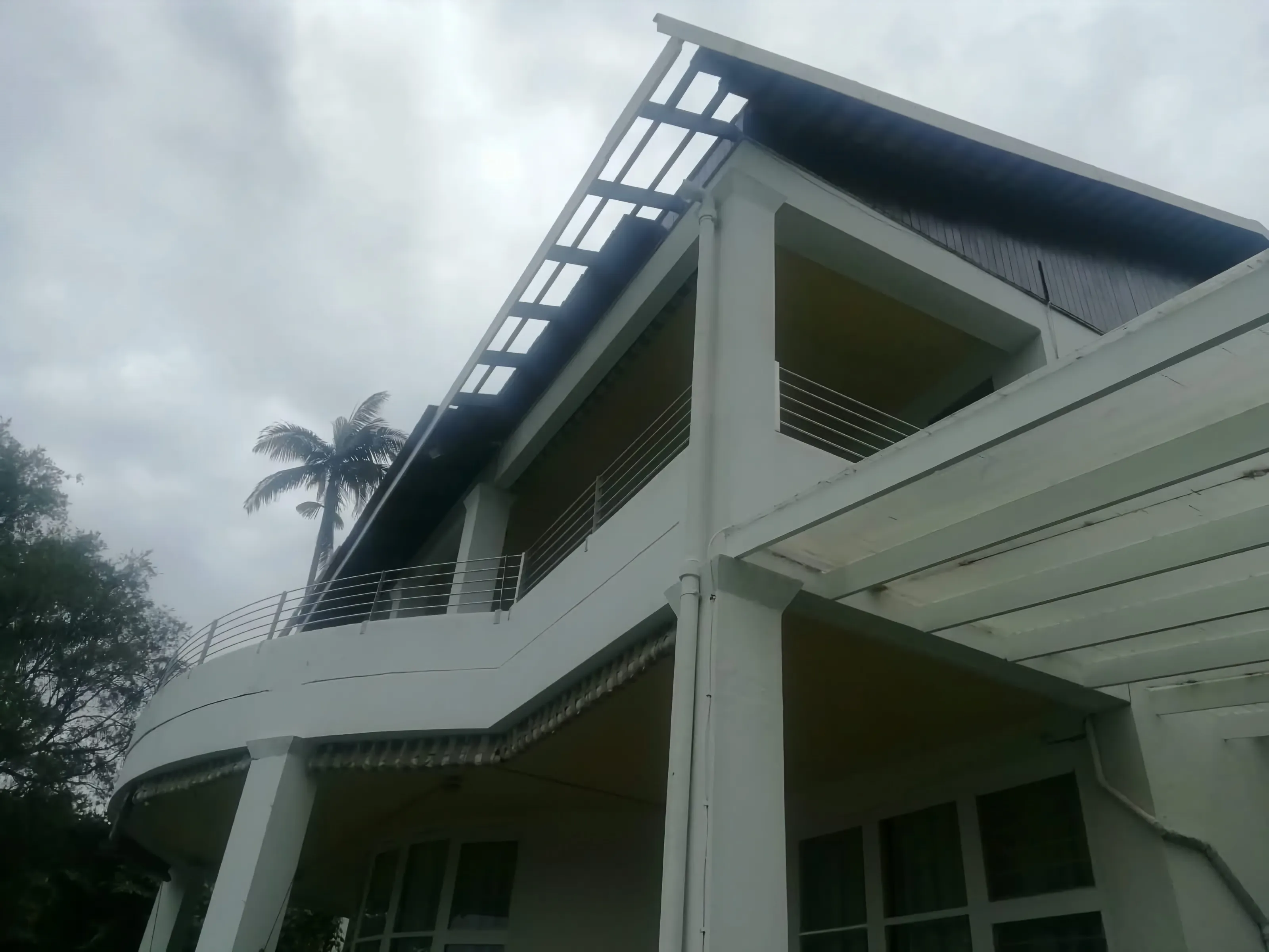 A double storey house with a dark sheeted roof, repaired by Roof Maintenance Services
