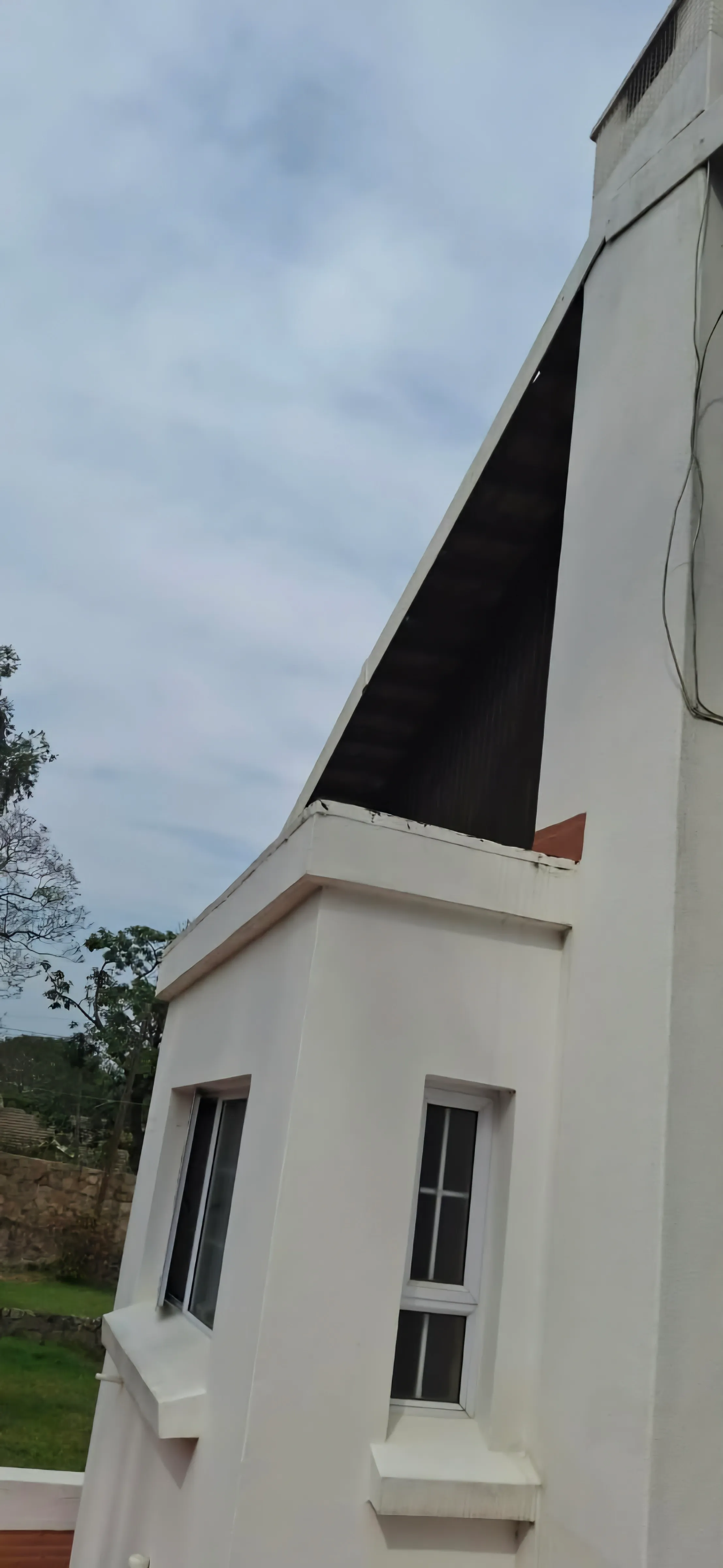 The edge of a steeply pitched sheeted roof where it meets a parapet